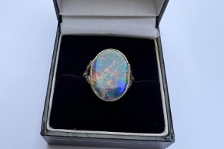 A large opal ring, the collet set opal showing a range of colours, measuring approximately 18mm