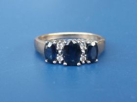 A modern three stone sapphire ring with four small diamonds on 9ct gold shank, finger size K and a