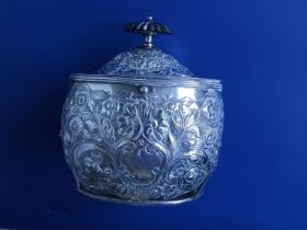 A Regency embossed silver oval tea caddy with ebony finial , decorated shells & flowers, two