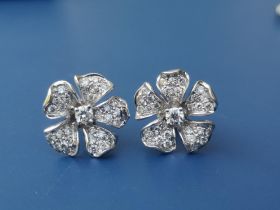 A pair of diamond pave set earrings of flowerhead form in white 750 metal, 15mm overall diameter. (