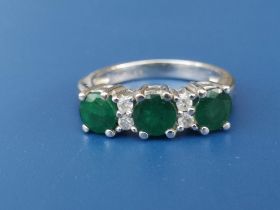 A modern three stone emerald ring with four small diamonds in 18ct white gold. Finger size K/L.