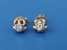 A small pair of illusion set diamond stud earrings in yellow metal.