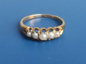 A yellow metal ring set with five small graduated split pearls. Finger size M.