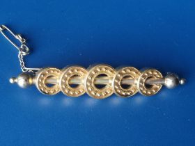 A late 19th/early 20thC yellow metal hollow bar brooch set with graduated millegrained hoops, 2.5".