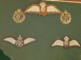 A glazed frame displaying an RFC cloth wings with cap badge and an RAF wings with badge, together