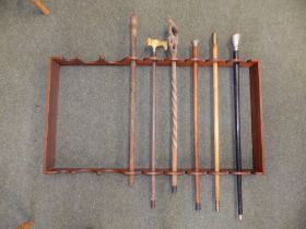 A mahogany wall rack for sticks together with six old walking sticks, the rack 41" x 22". (7)