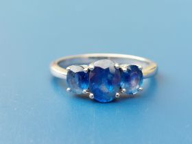 A modern three stone sapphire claw set 18ct white gold ring. Finger size O.