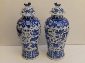 A pair of Chinese blue & white porcelain covered vases, lion finials to lids, the baluster bodies
