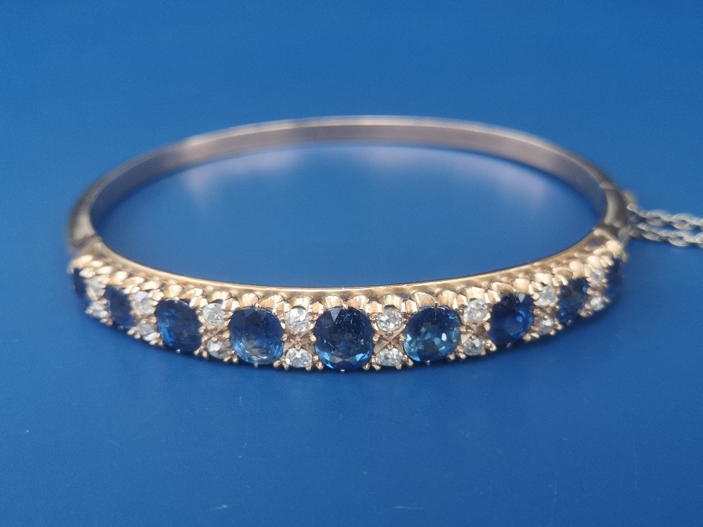 A Victorian sapphire & diamond claw set gold bangle, having nine graduated cushion cut sapphires and