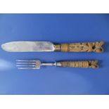 An early 20thC knife & fork with carved wooden handles, each surmounted by a stylised lion, the fork
