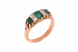 A diamond and emerald ring, three baguette cut emeralds flanking four diamonds, ring marked TRT 22,