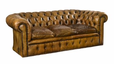 A large green leather upholstered Chesterfield style settee, deep buttoned with loose cushions.