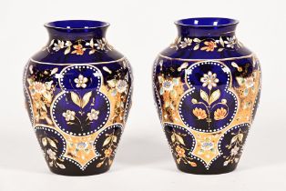 A pair of late 19th century Bohemian blue glass vases, with enamel decoration and gilding.