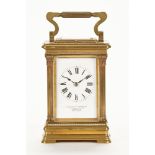 An Edwardian brass and glass panelled carriage clock, with Roman numerals and white enamel dial,