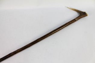 A hazel shafted walking stick with a red stag antler handle. Overall length 123 cm.