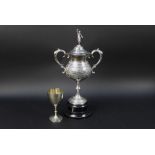 Two hound trailing trophies, the first with classical finial and with twin handles,