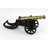 A brass cannon, length 29 cm on a cast iron carriage. Length 38 cm.