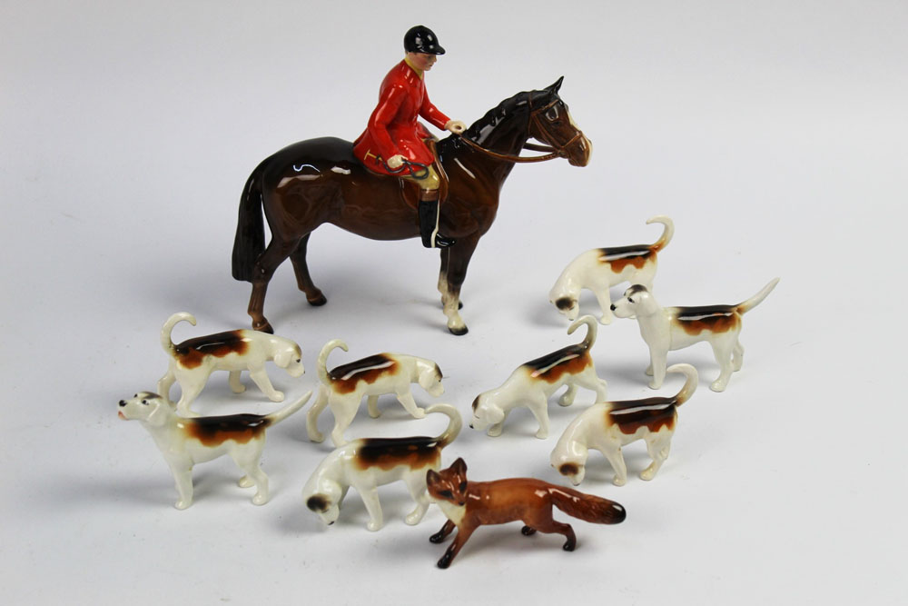 A Beswick foxhunting group with huntsman on brown horse, eight first version hounds and a fox.