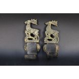 A pair of brass and leather gun wall hanging mounts, decorated with stag and hounds,