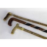 Three walking sticks, the first with hazel shaft, brass handle.