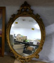 Oval wall mirror in gilt effect ornate frame,