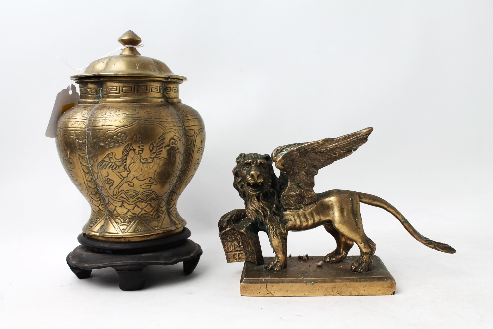 Glass griffin and brass griffin decorated lidded jar on wooden stand,