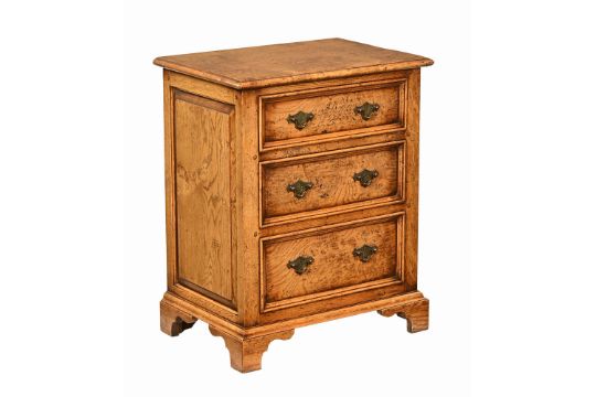 A George III style Pollard oak bedside chest of three drawers, raised on bracket feet.