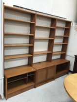 A modern teak lounge unit with three banks of open shelving above a central pair of cupboards and
