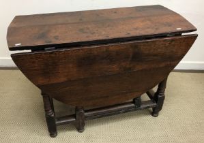 An 18th Century oak gate leg drop leaf dining table on turned and ringed supports to block feet