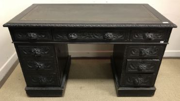 A Victorian carved oak Gothic Revival kneehole desk, the top with tooled and gilded leather insert,