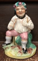 A 19th Century Staffordshire pottery figure of Bacchus seated upon a barrel, a beaker in his hand,