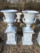A smaller pair of blue painted cast iron garden urns, on plinth bases,