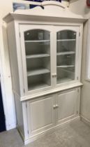 A pair of modern white painted bookcase cabinets with fretwork pediments over two arched panelled