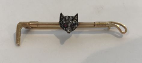 A 15-carat gold mounted diamond and ruby fox mask and whip stock pin, 4.6 cm wide, 3.
