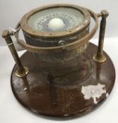 A nautical gyroscopic compass with brass mounts stamped "Nautical 2075" housed on a wooden base,