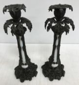 A pair of bronze candlesticks with white glass centres, the candlesticks of foliate design,