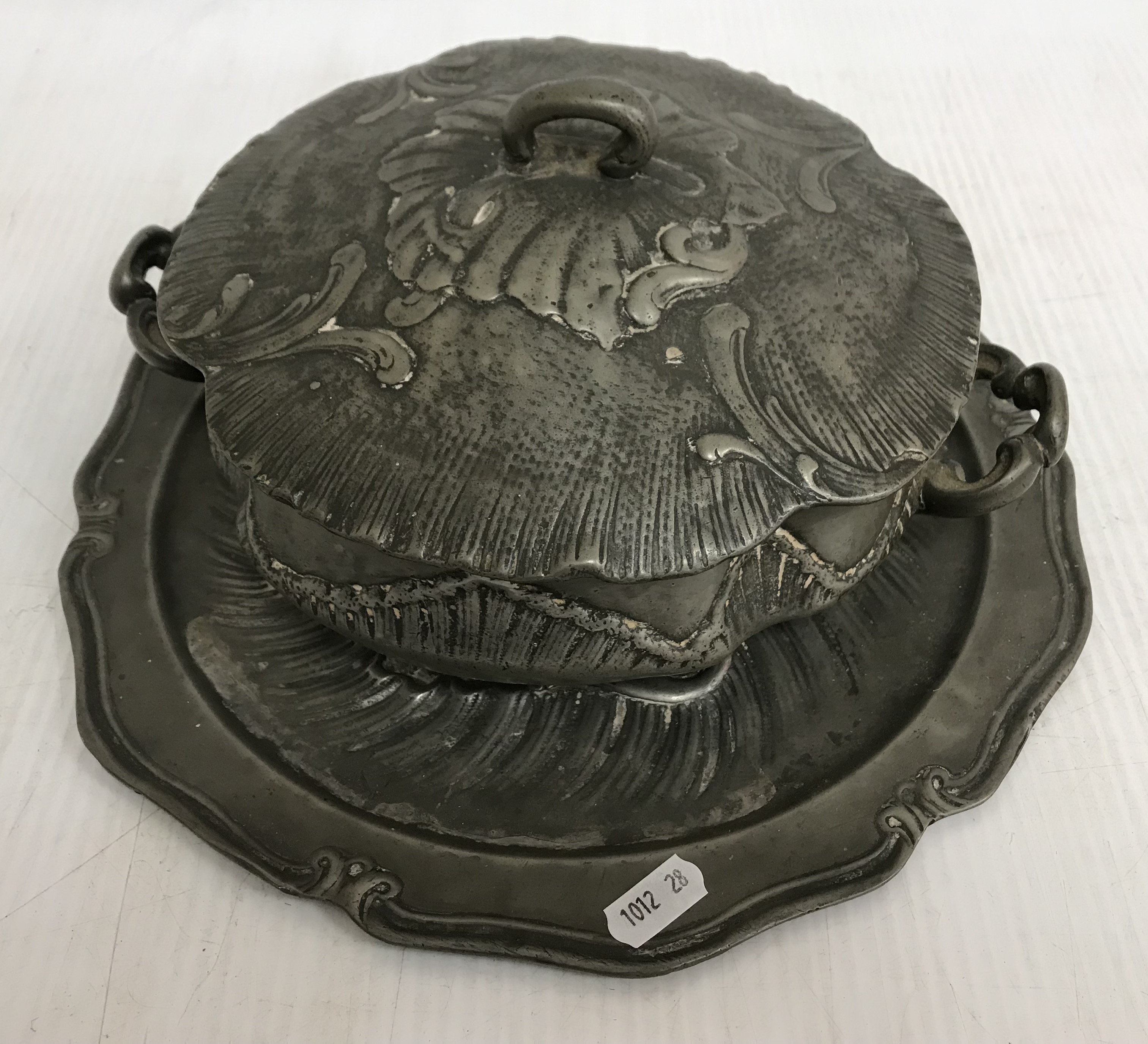 An early 19th Century German heavy embossed pewter tureen and associated plate base bearing pewter