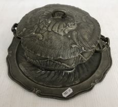 An early 19th Century German heavy embossed pewter tureen and associated plate base bearing pewter