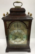 A George III mahogany cased mantle clock, the caddy top with brass handle and pineapple finials,