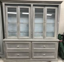 A grey painted cabinet with two pairs of sliding glazed doors enclosing adjustable shelving over a