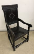 An oak Wainscott type armchair in the 17th Century style with carved top rail over a panelled back