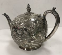 A Victorian silver bullet-shaped tea pot with all over floral and foliate embossed decoration (by