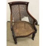 A William IV mahogany framed bérgère chair with scroll back and lotus leaf carved arms on turned