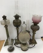 A collection of five various oil lamps including a Corinthian column lamp with embossed copper