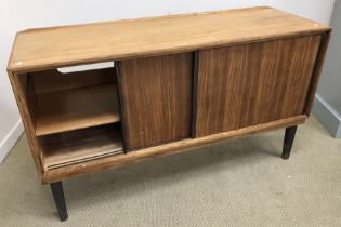 A 1960s teak sideboard, the plain top over two sliding doors, on ebonised supports,