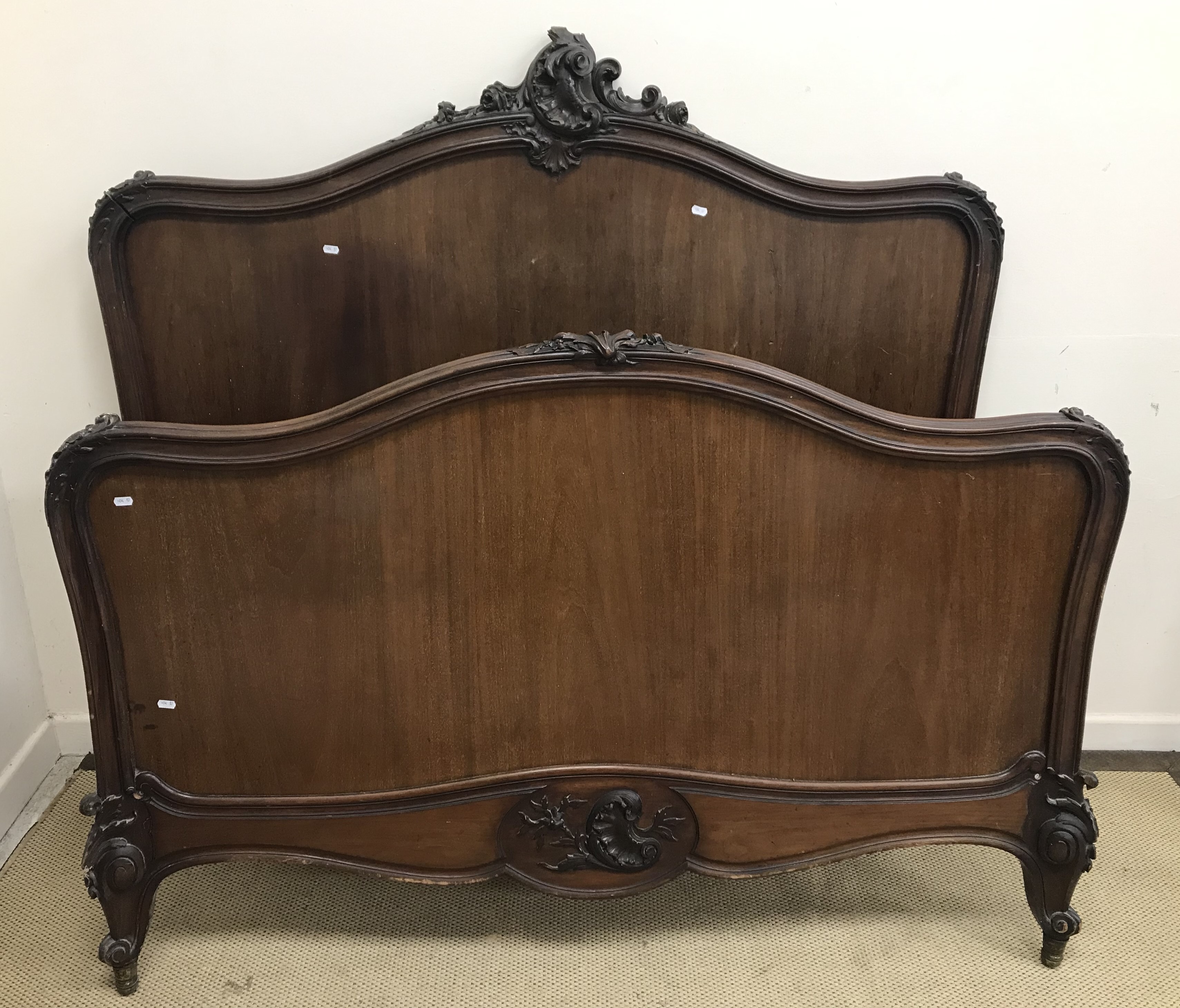 A pair of early 20th Century mahogany and carved bed ends in the Louis XV taste,