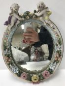 A late 19th Century Continental porcelain framed oval wall mirror with applied cherubs and floral