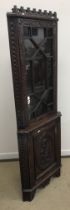 A 20th Century oak and carved free-standing corner cupboard in the 17th Century style with all-over