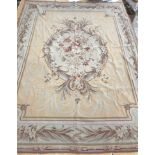 A needlepoint rug, the peach ground set with scrolling foliate design within a stepped border,