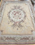 A needlepoint rug, the peach ground set with scrolling foliate design within a stepped border,